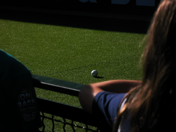 A baseball in bright sunlight sitting on green artificial turf in the bullpen at T-Mobile Park.